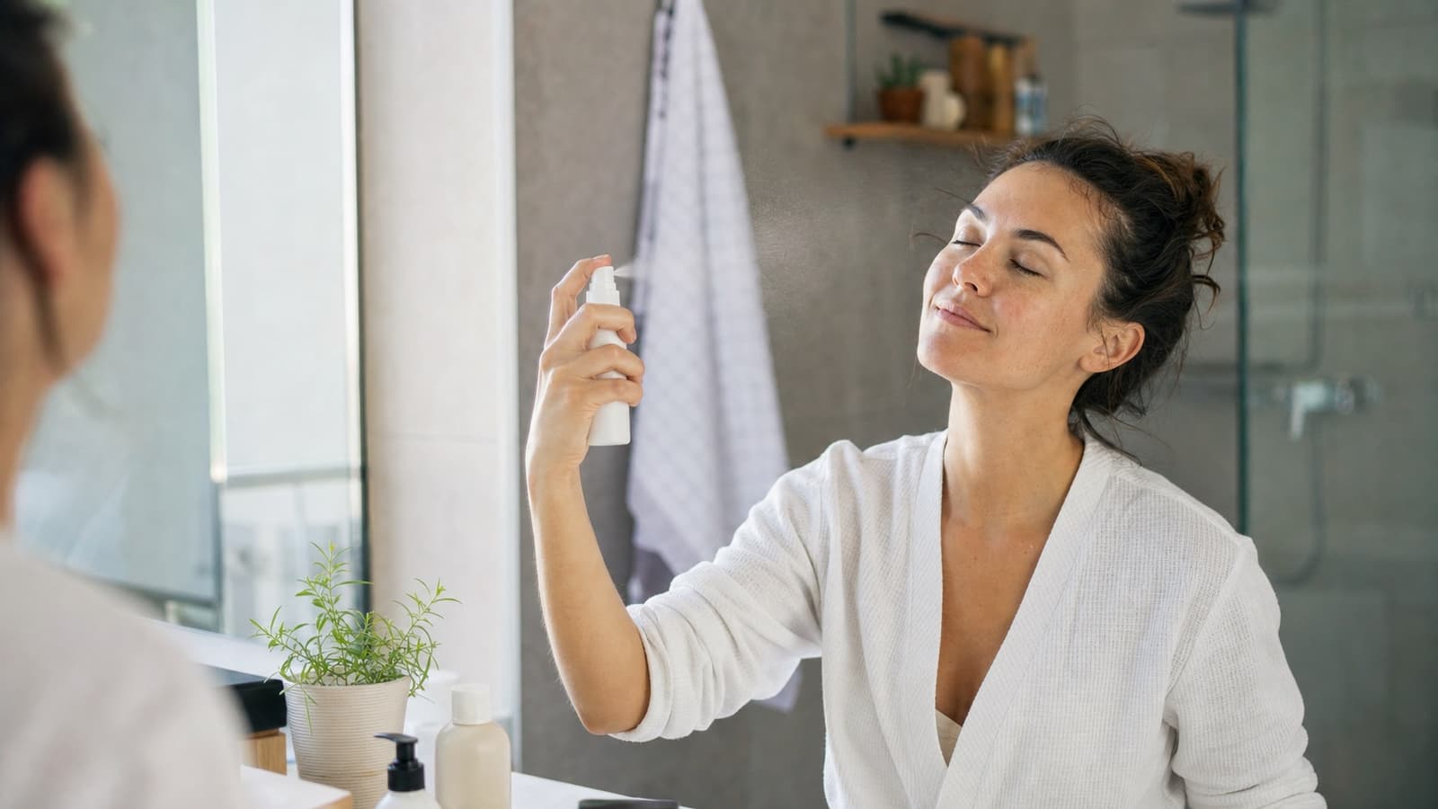 Adult using a face mist in a bright bathroom after cleansing